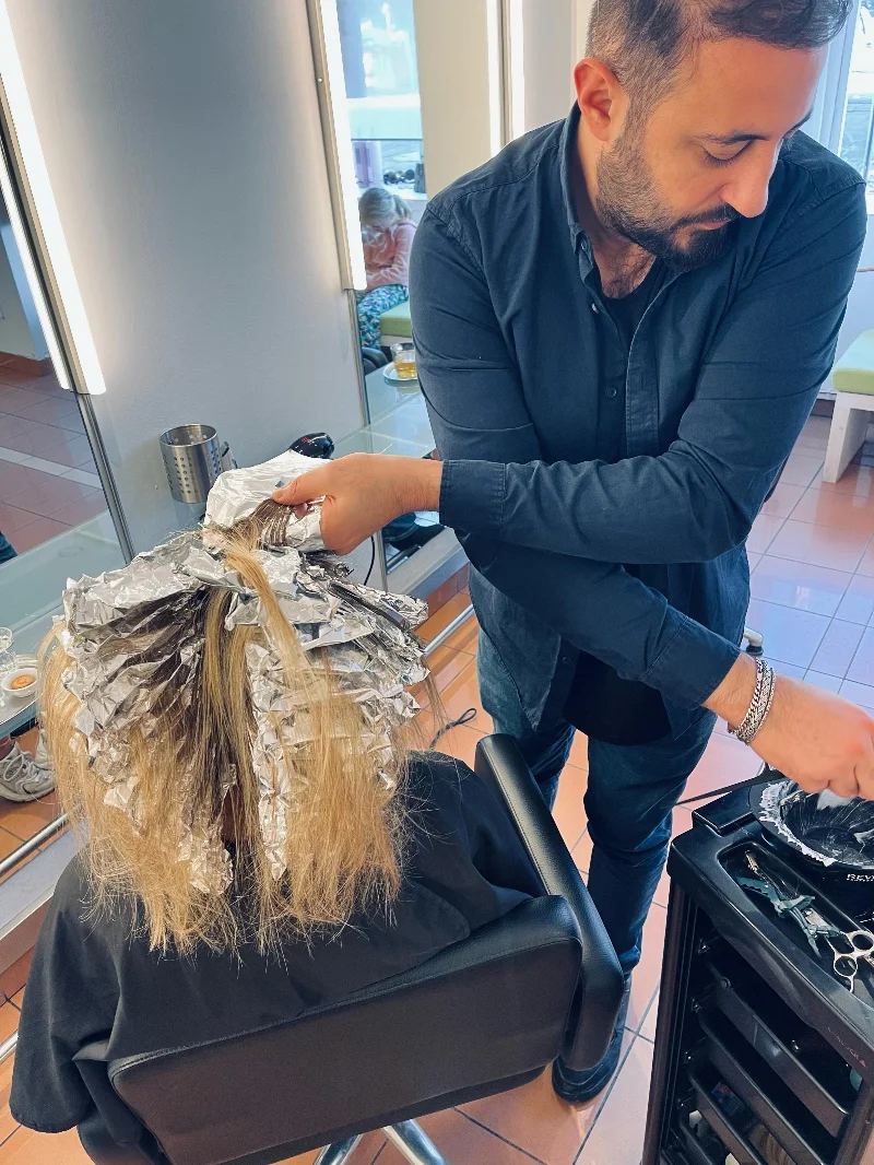 Stylist bei AG Haarwelt setzt Strähnen in Folientechnik